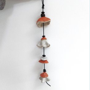 Vindklokke i orange og sandfarvet glasur. Har sort l�dersnor og m�rke tr�perler. 